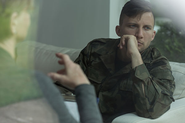 man in military uniform looking out window, depressed