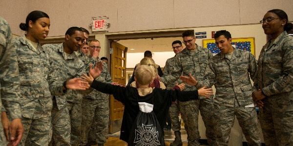 military kid gets high fives from service members in uniform