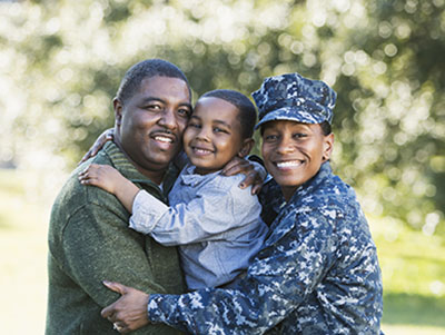 Woman in military uniform hugging her son and husband